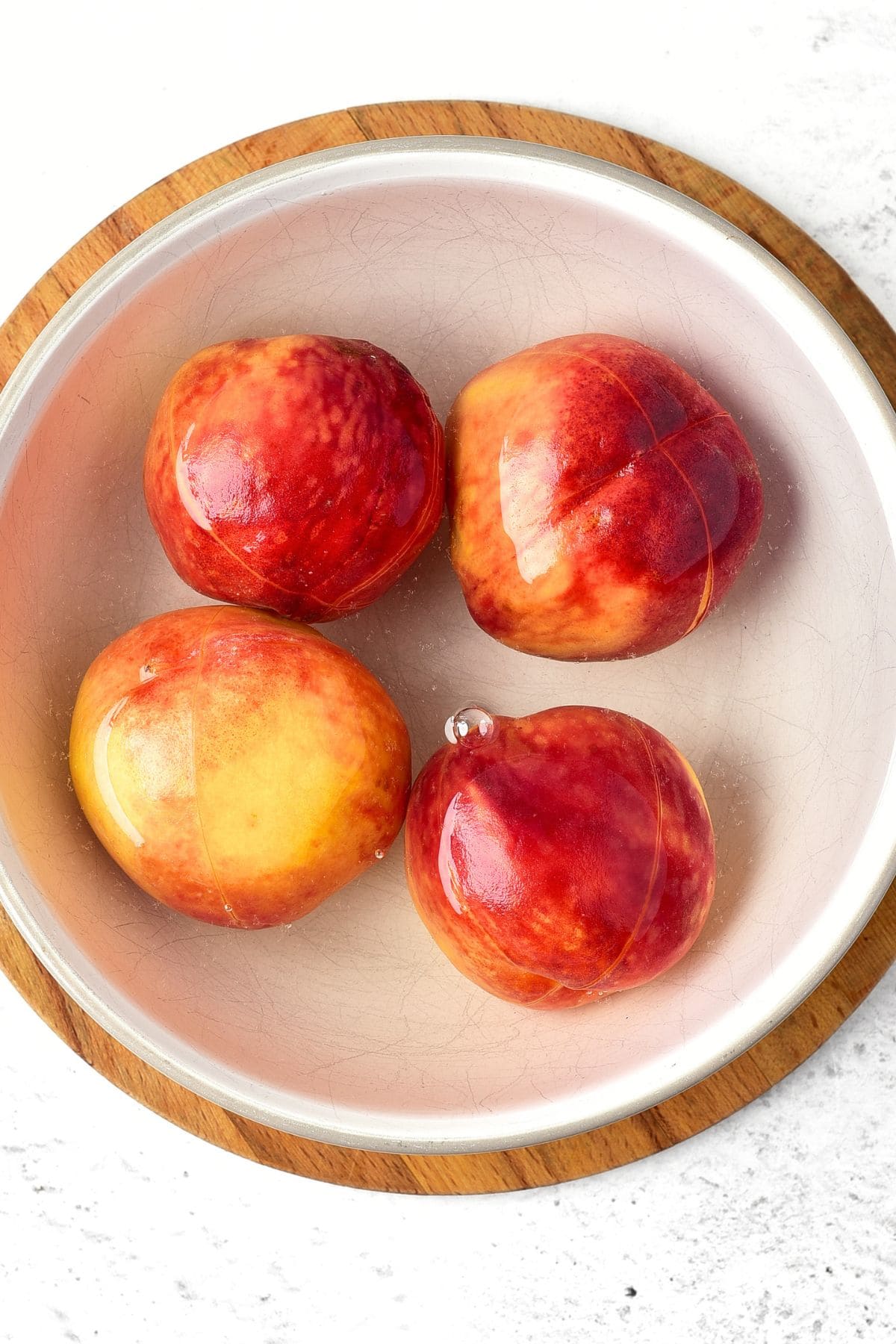 Sweet and Spicy Peach Jam with Jalapenos Scored peaches in bowl of water