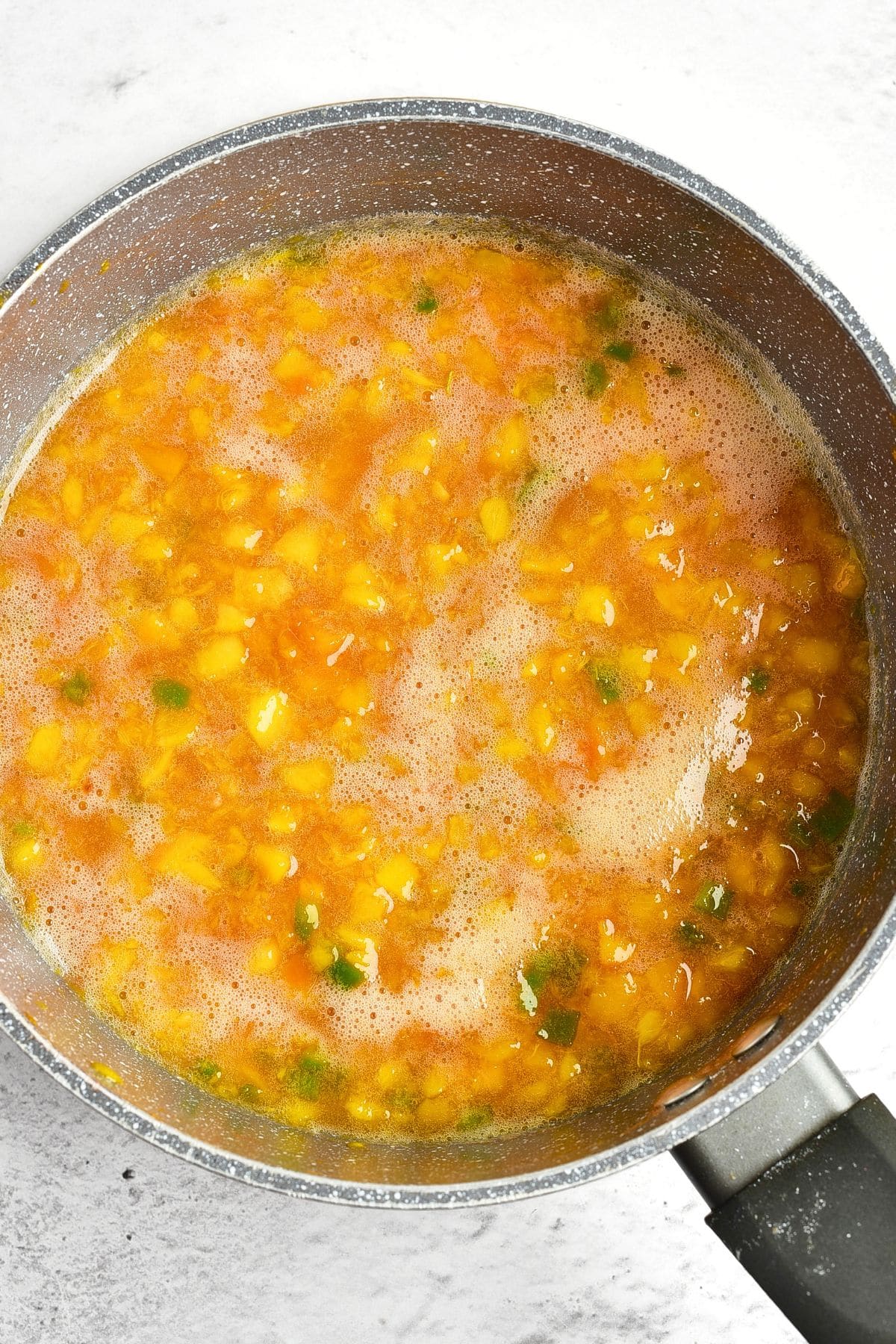 Sweet and Spicy Peach Jam Diced peaches and jalapeno mixture cooking in saucepan