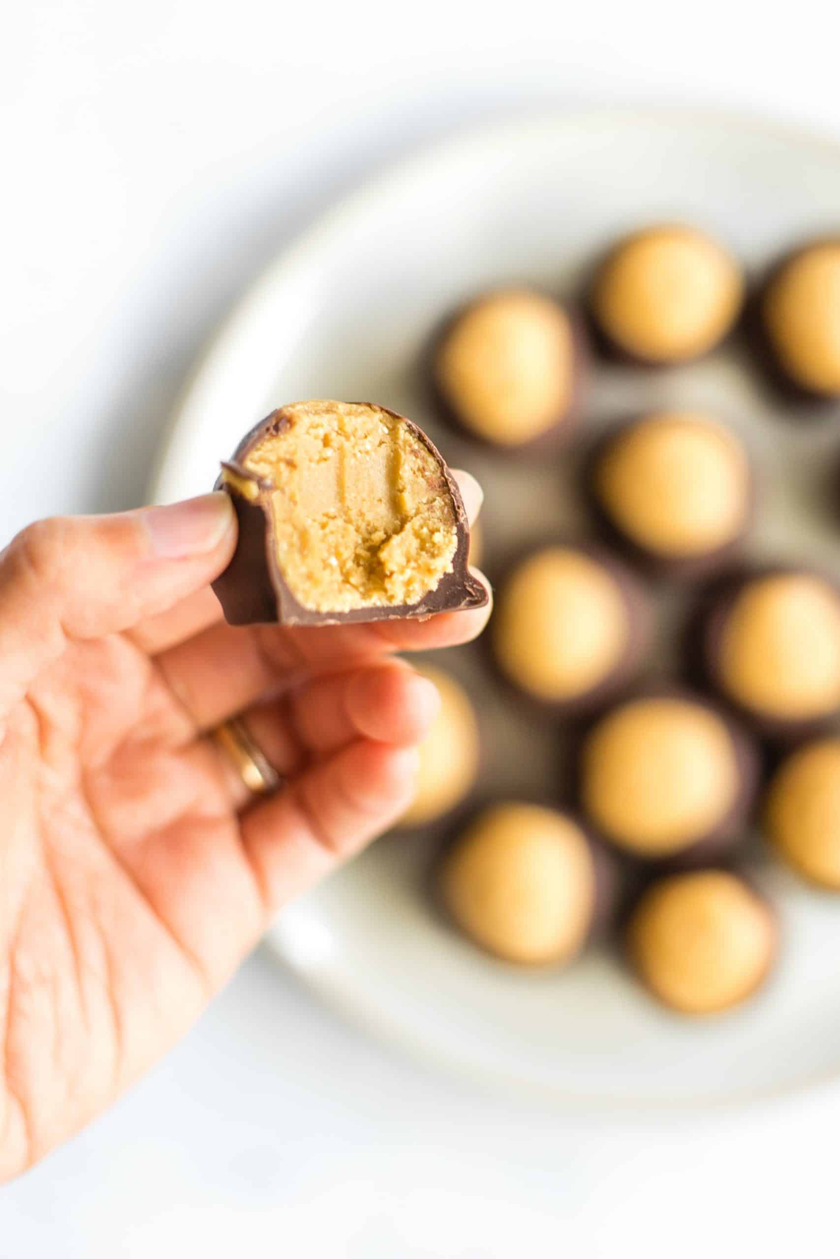 A half-eaten peanut butter buckeye showing the creamy peanut butter filling.