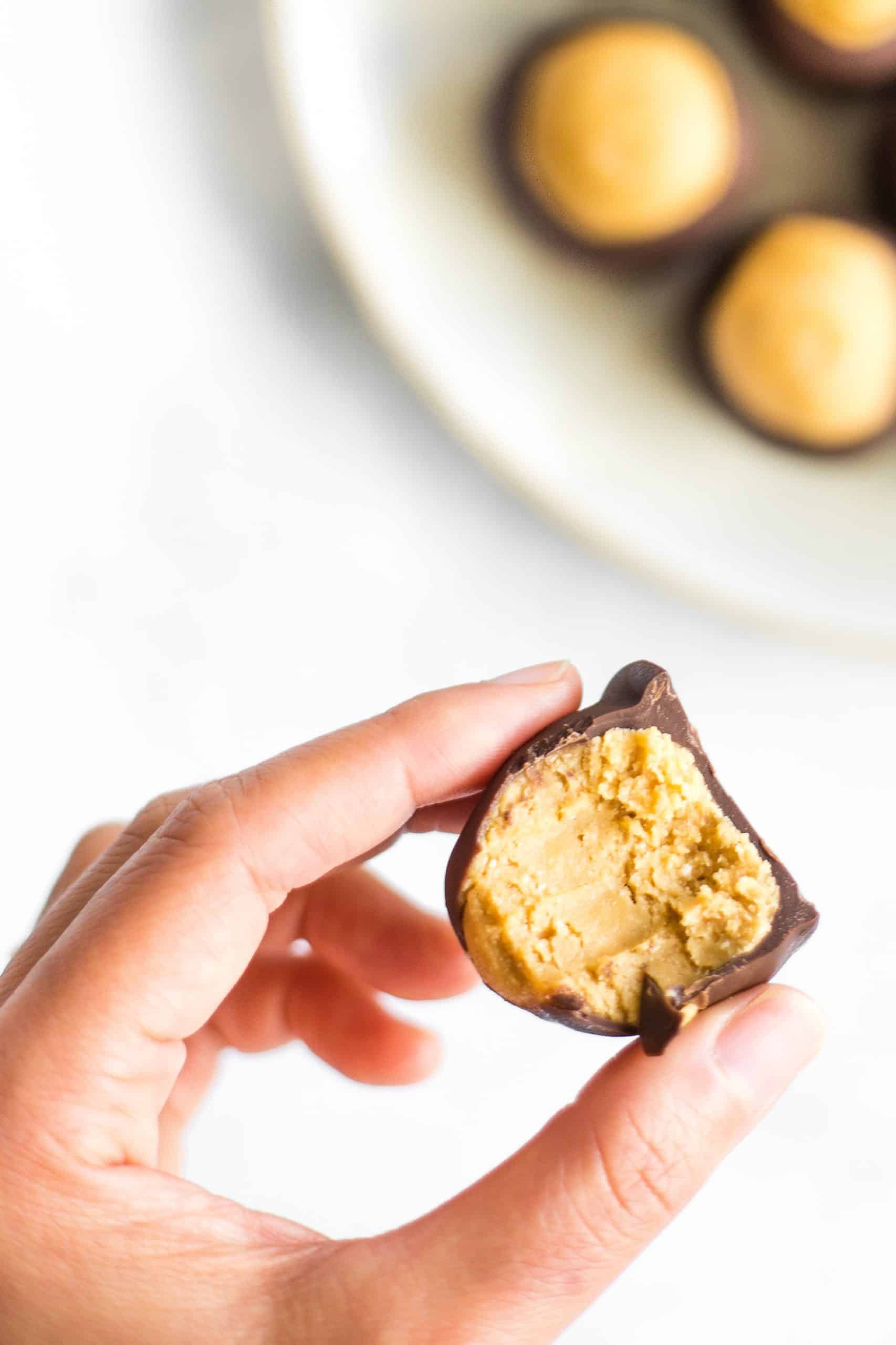 Holding up a half eaten peanut butter ball and showing the closeup of the inside.