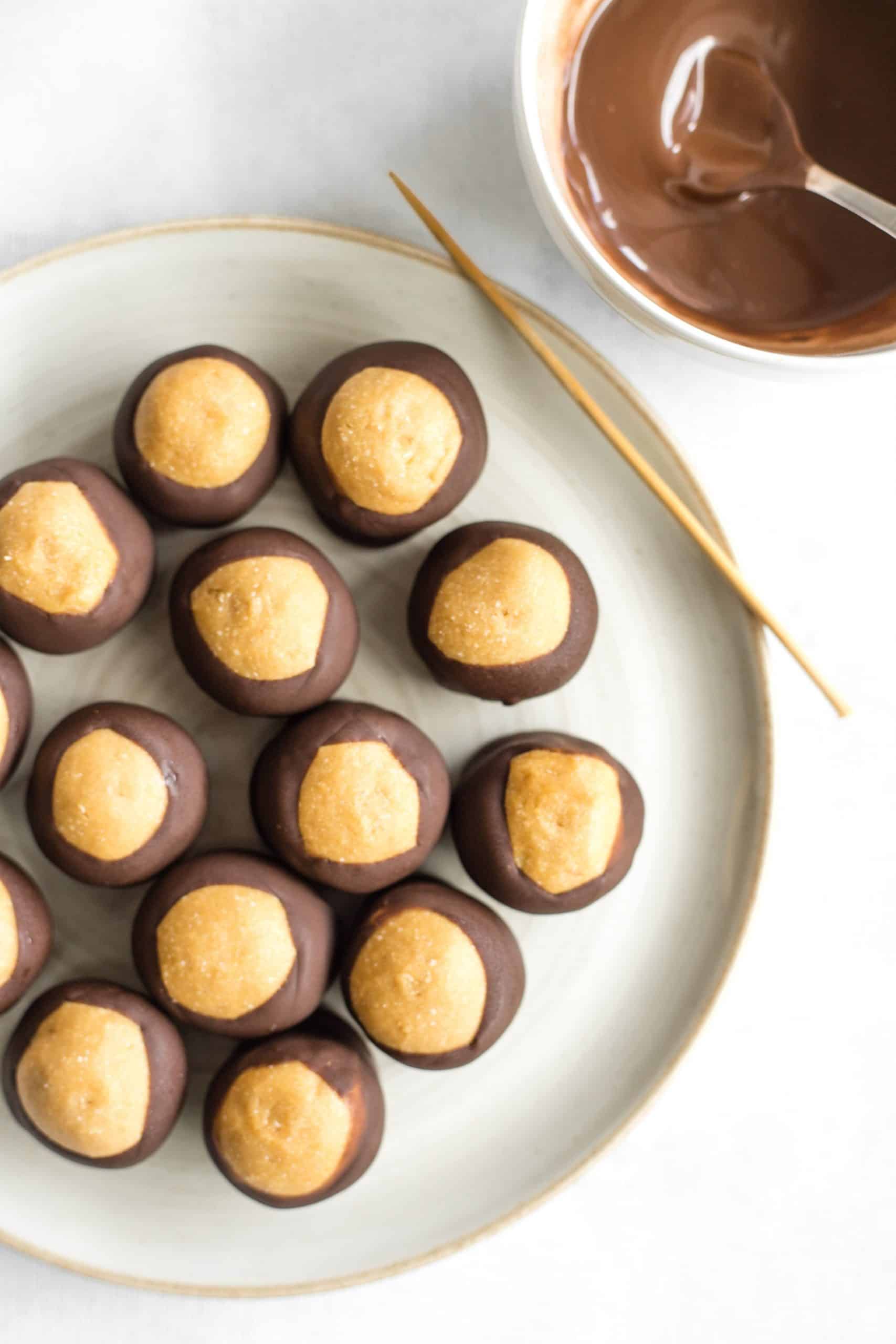 A plate of buckeye balls  and a bowl of melted chocolate.