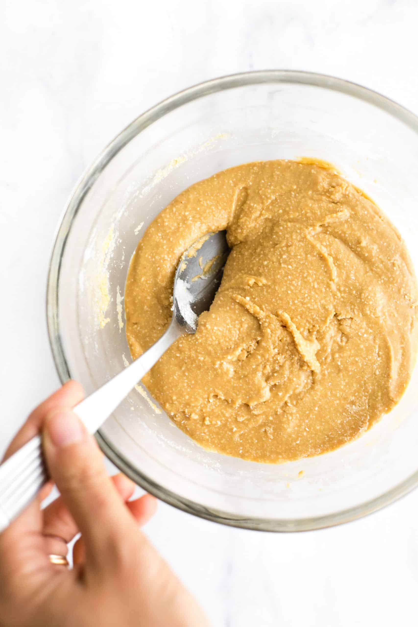 Mixing a peanut butter dough in a glass bowl.