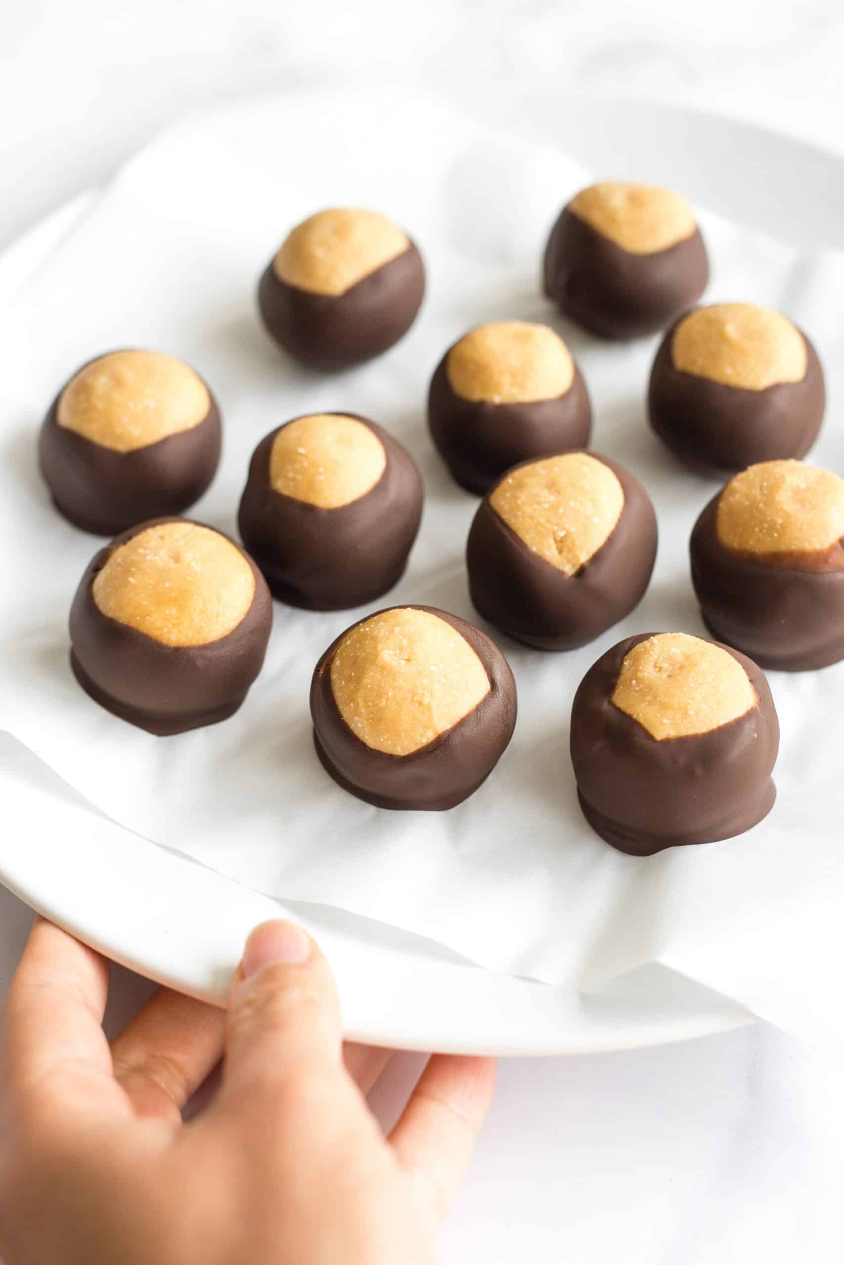 Holding a plate of chocolate-coated peanut butter balls.