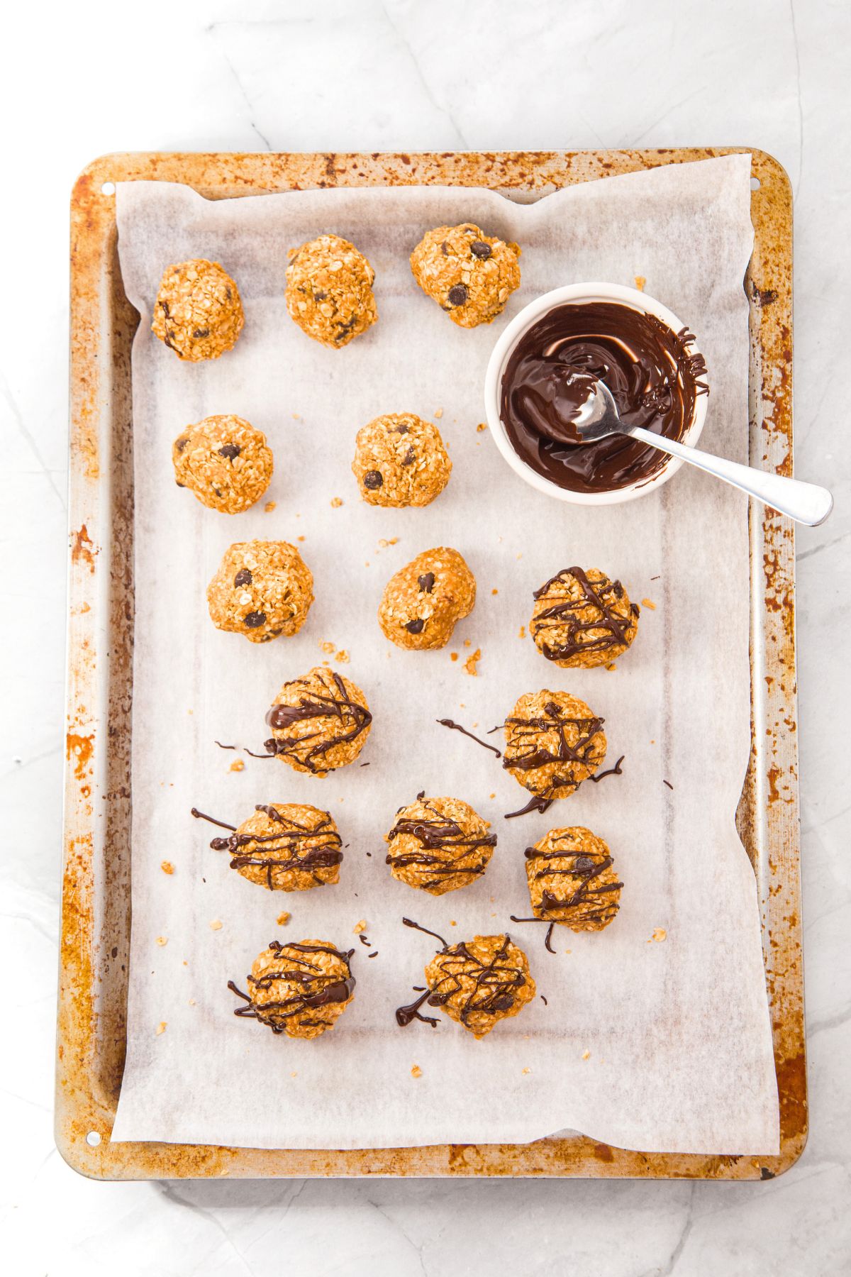 Chocolate drizzled oatmeal and peanut butter energy balls on baking sheet