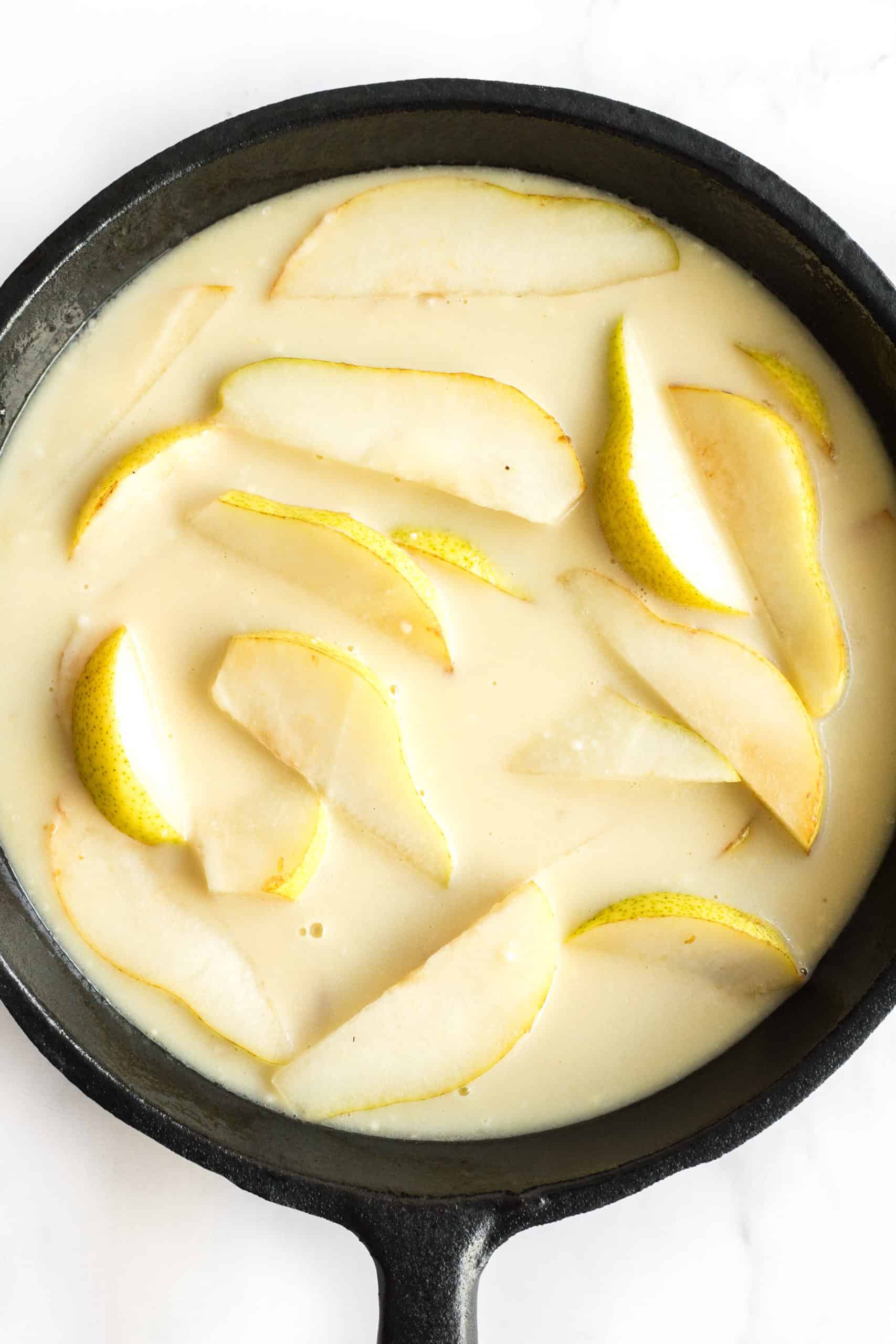 Mise en place for pear custard pie (pear slices with custard batter in cast iron skillet)