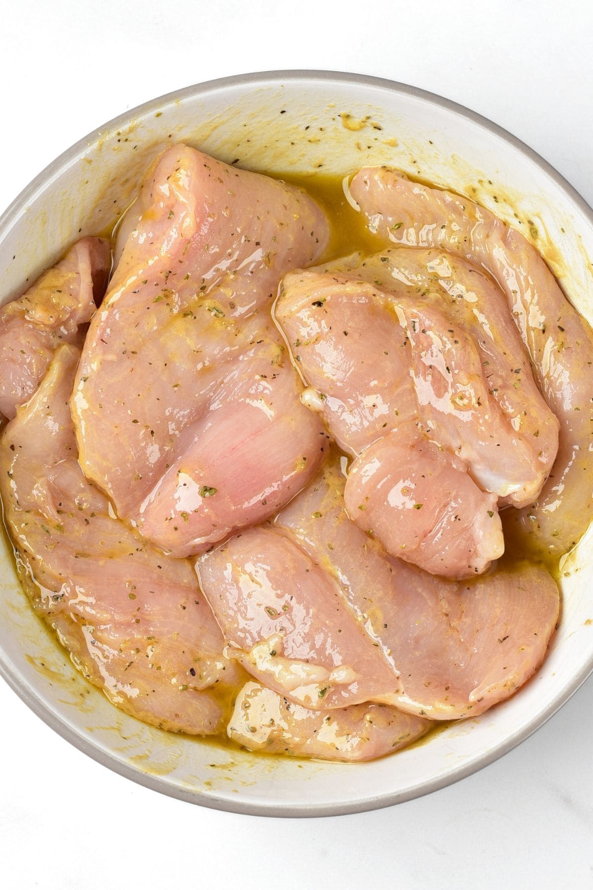 Marinated chicken breast fillets in bowl.