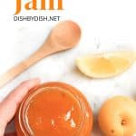 Hand holding a jar of apricot jam,
