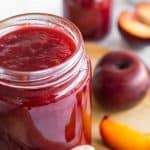 Hand holding a jar of plum jam