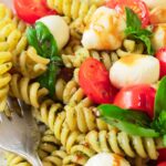 A fork on a plate of caprese pasta salad.