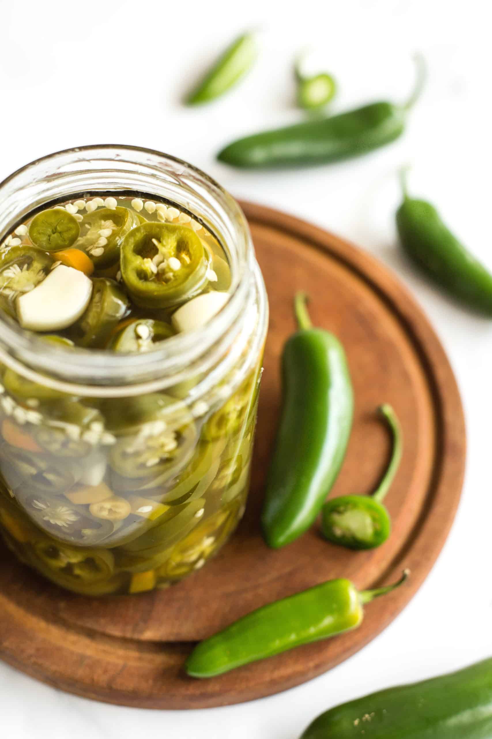 A jar of pickled jalapeños on a wooden board.