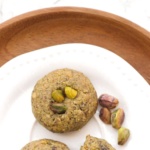 A plate of pistachio cookies on wooden plate.