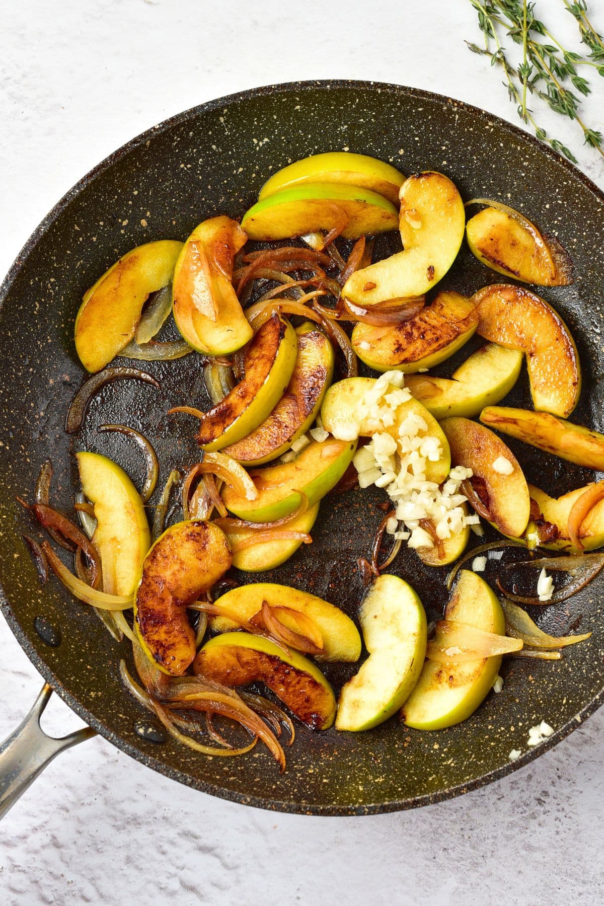 Sautéing sliced apples, onions and garlic in skillet