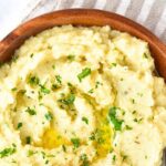 Top down view of a bowl of cauliflower potato mash on kitchen towel.