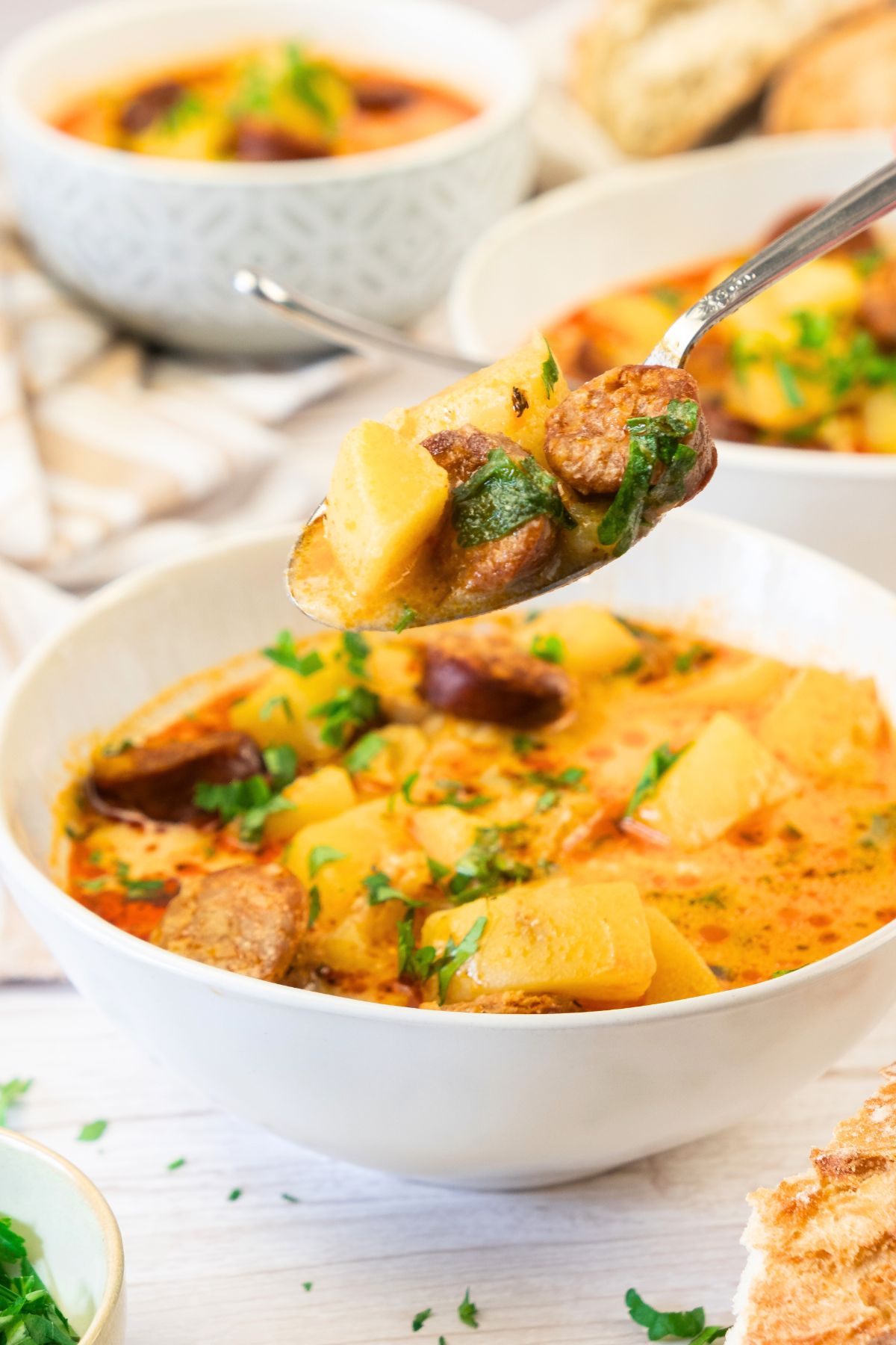 Holding up a spoonful of chorizo slices and potato chunks.