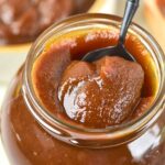 Holding up a spoonful of pumpkin apple butter from a glass jar