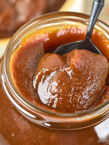 Holding up a spoonful of pumpkin apple butter from a glass jar