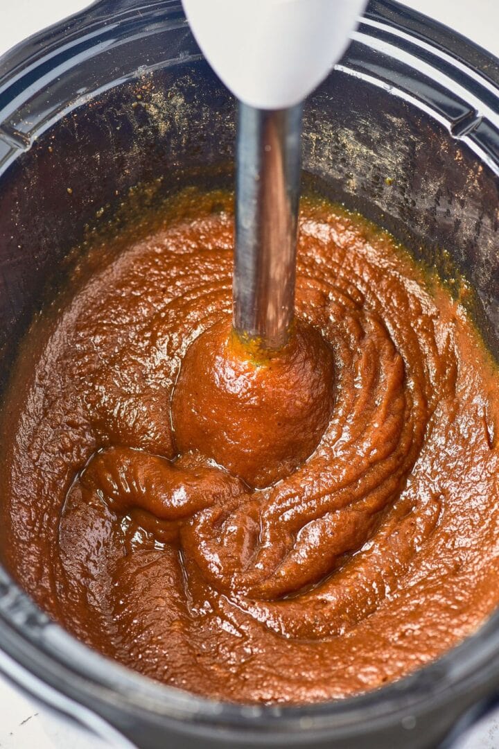Using an immersion blender to blend apples and pumpkin.