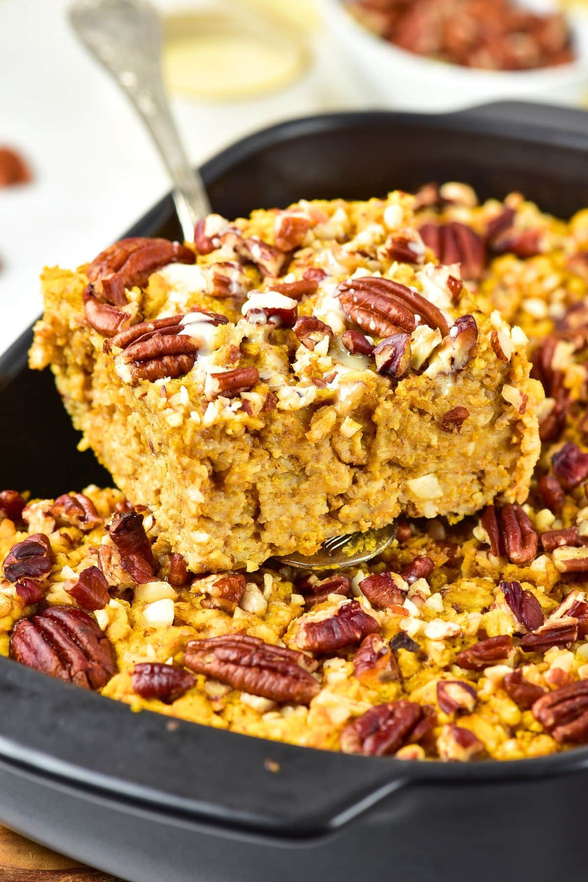 Holding up a portion of pumpkin spice baked oatmeal from casserole dish