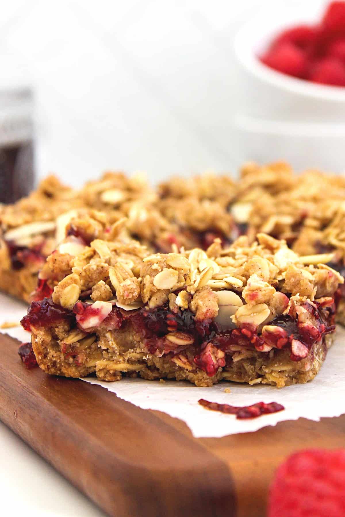 Up close shot of raspberry jam oatmeal bars on parchment-lined board.