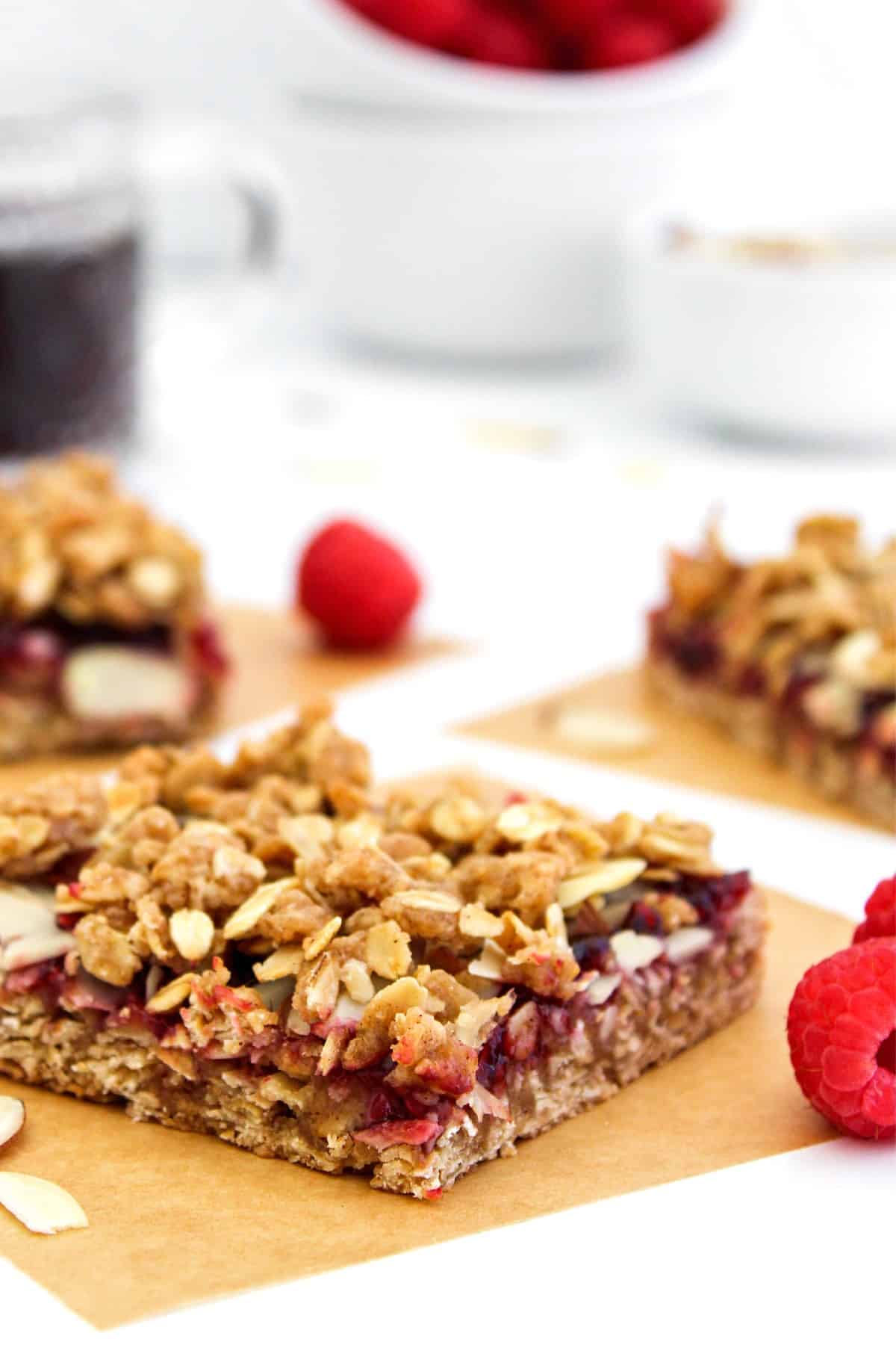 A portion of raspberry oatmeal bars on brown parchment paper.