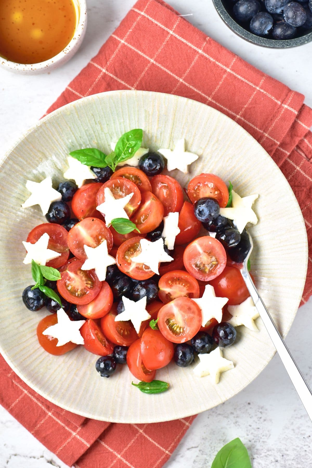 A plate of caprese salad with blueberries on red towel