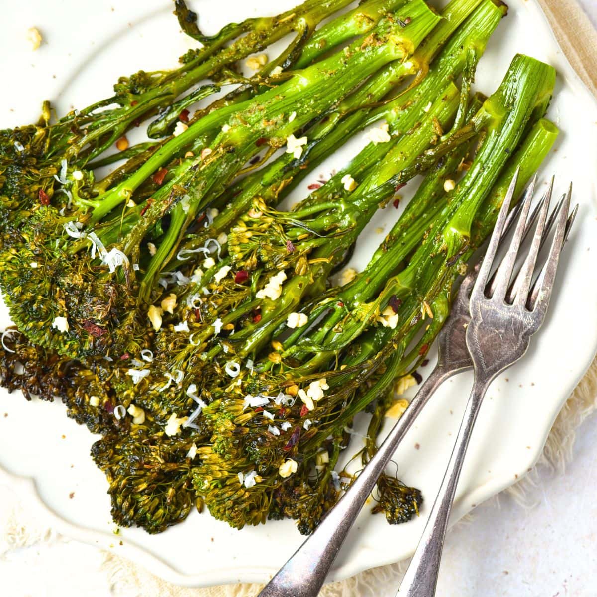 Top down view of a plate of roasted broccolini with forks