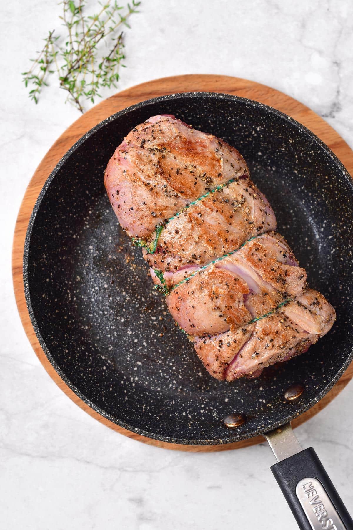 Searing rolled lamb in skillet.