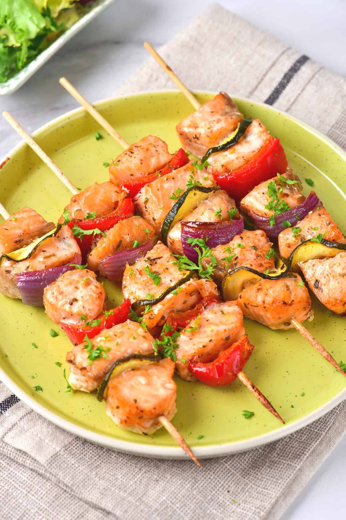 Up close view of salmon skewers on green plate.