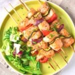 A plate of salmon kabobs and salad.
