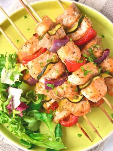 A plate of salmon kabobs and salad.