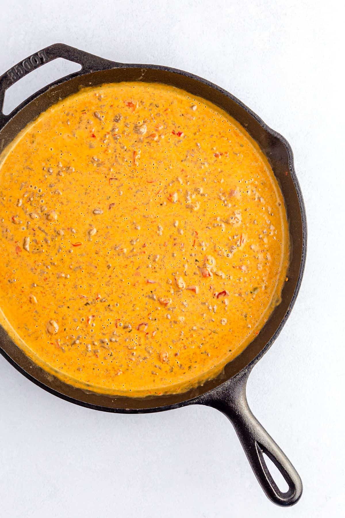 A cast iron skillet with cheese dip.