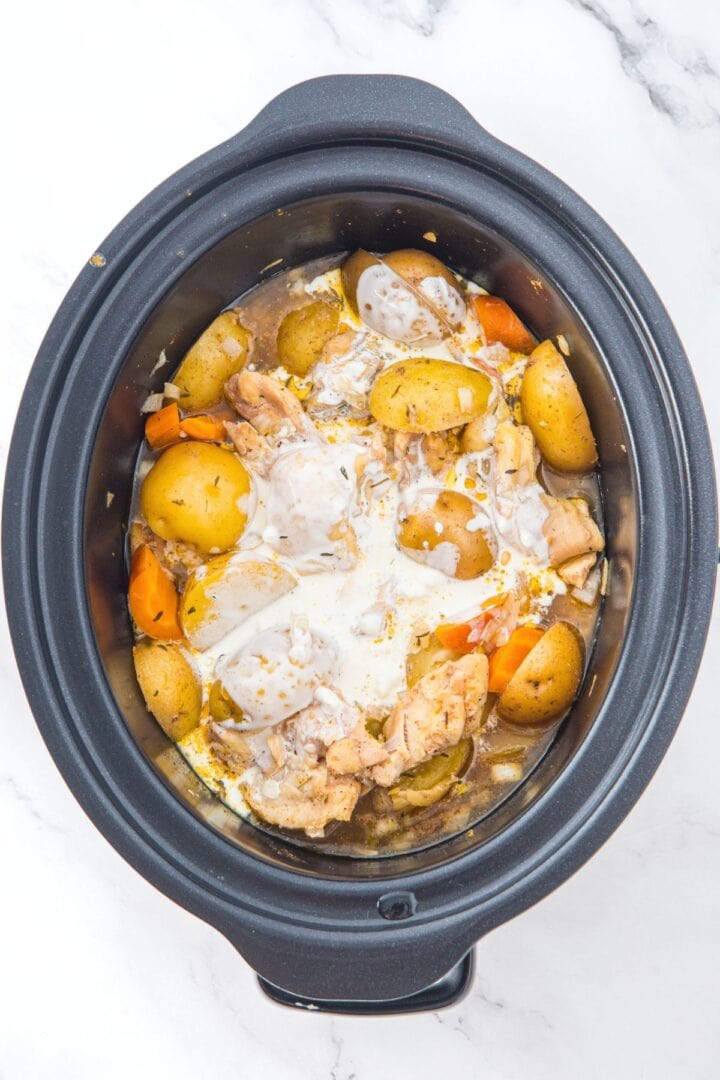 Cream mixture splashed on top of cooked chicken and potatoes in slow cooker 