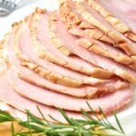 Up close view of sliced ham and fresh rosemary sprig