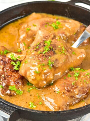 Smothered chicken thighs in cast iron skillet