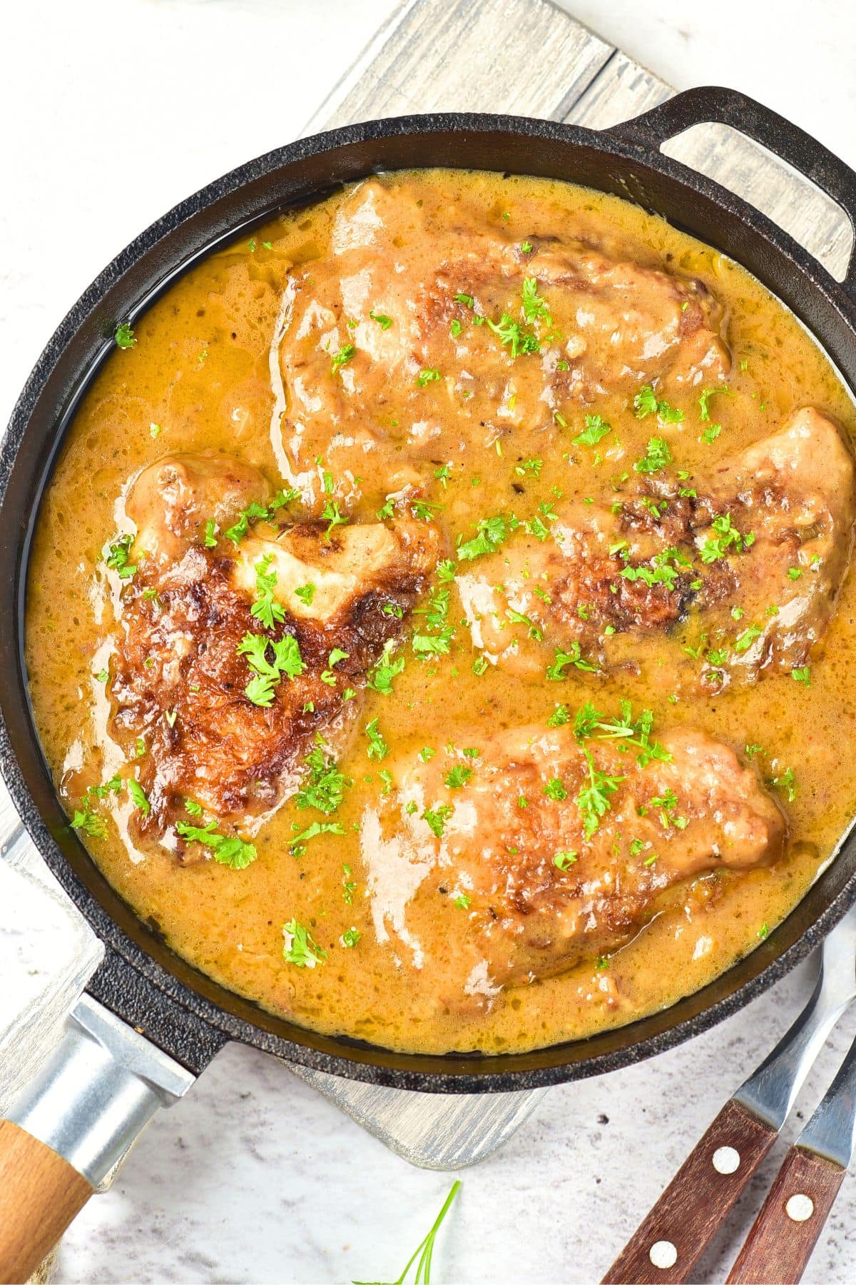 Southern Smothered Chicken Thighs (Gluten-Free, Dairy-Free) Top down view of a skillet with smothered chicken thighs in onion gravy.