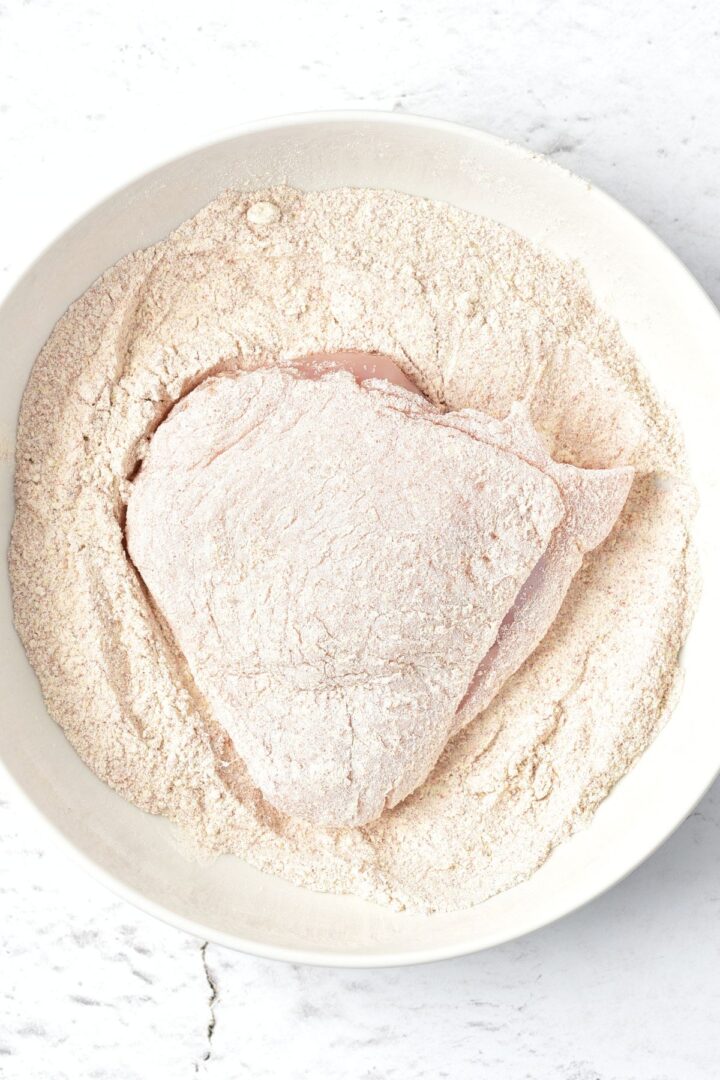 Coating chicken thigh in flour mixture.