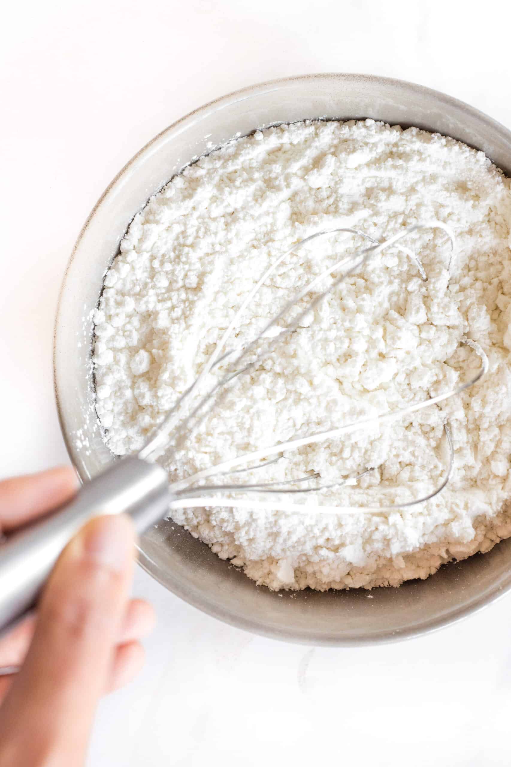 Whisking flour in a grey bowl.