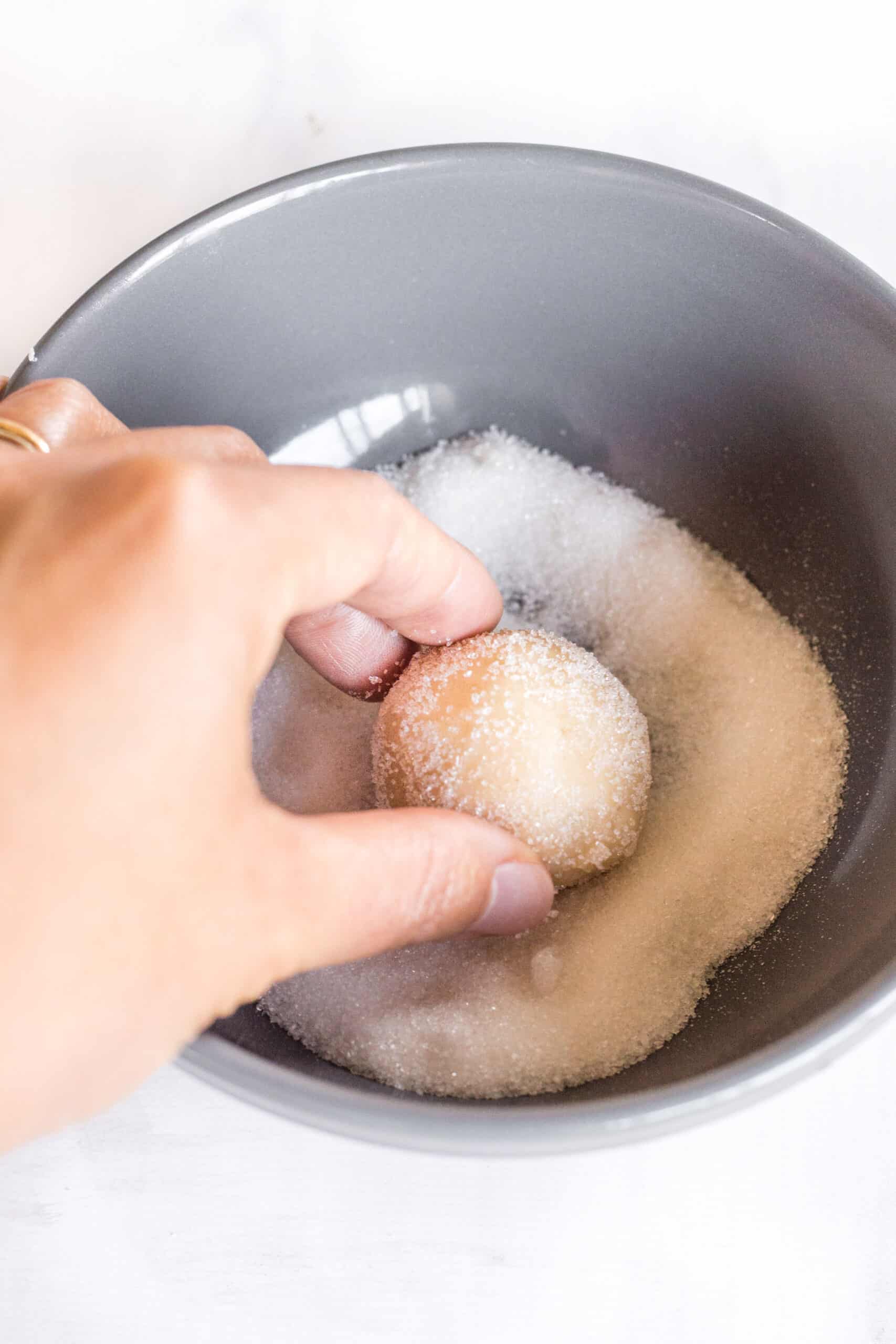 Rolling a cookie dough ball in sugar.