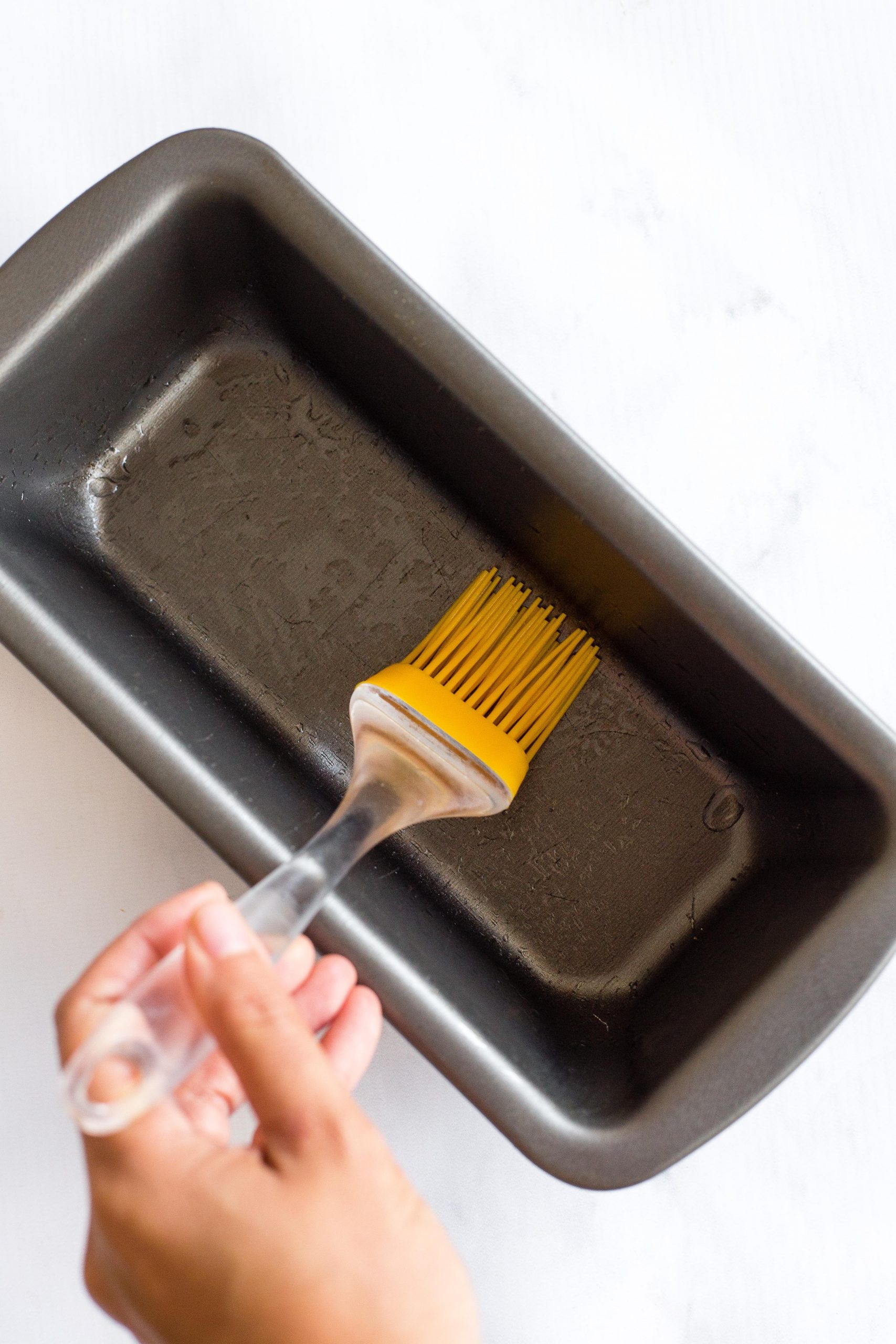 Greasing a metal loaf pan.