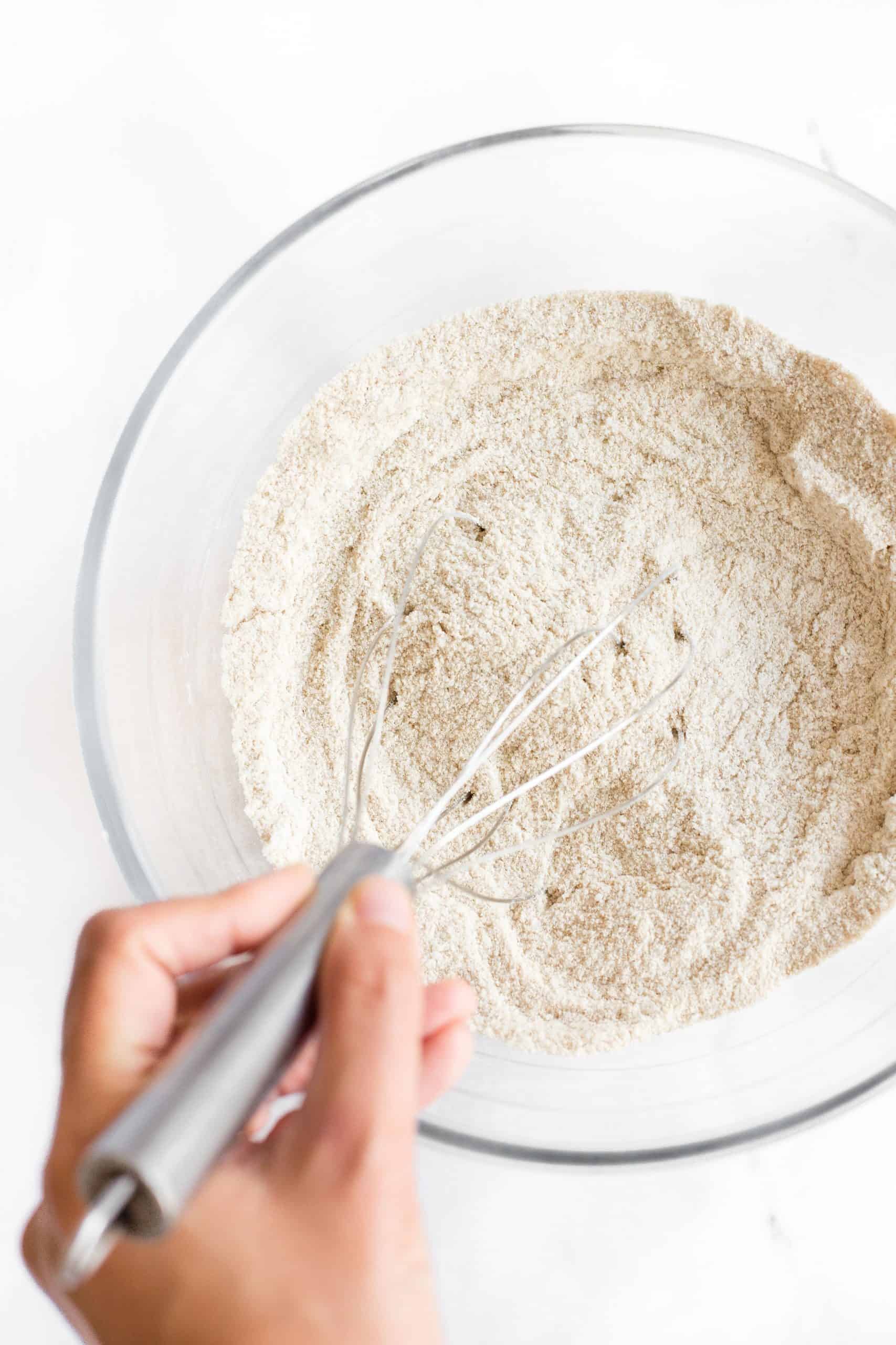 Whisking dry ingredients in a large glass bowl.