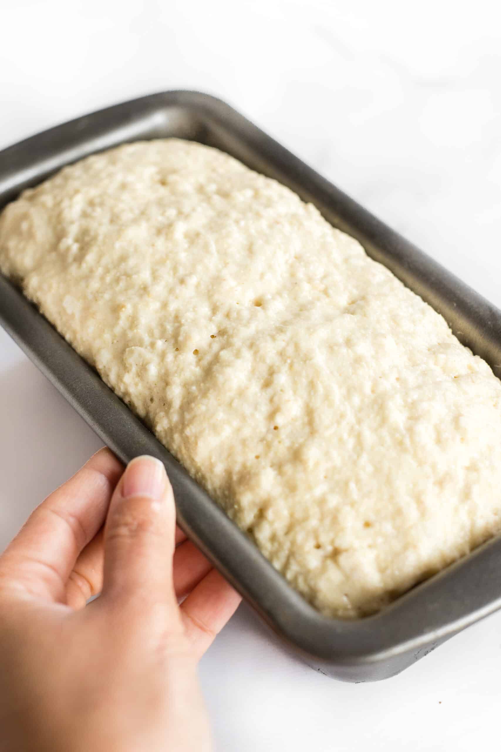 Holding a pan with rising bread dough.