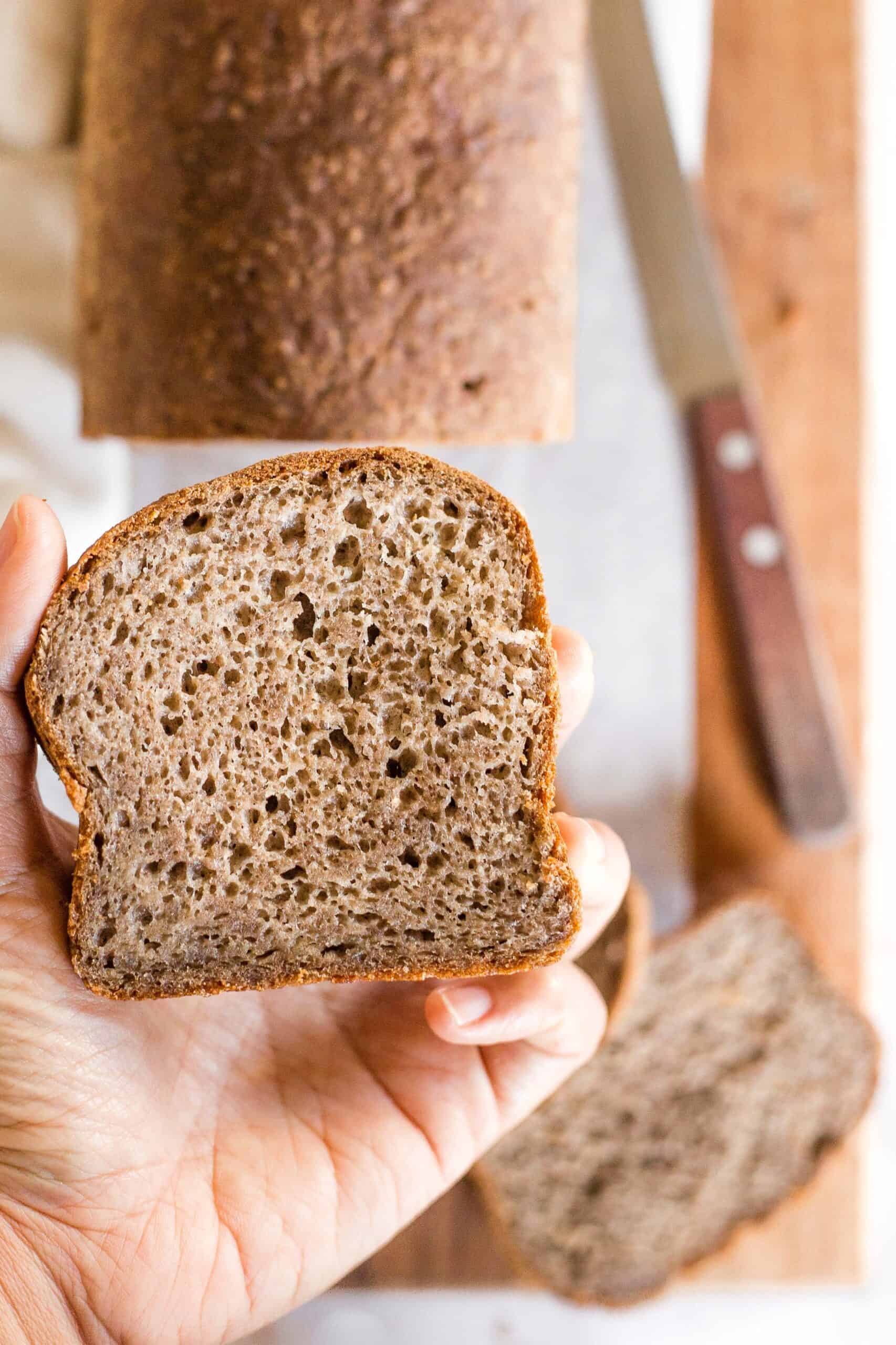 Holding up a slice of teff flour bread.