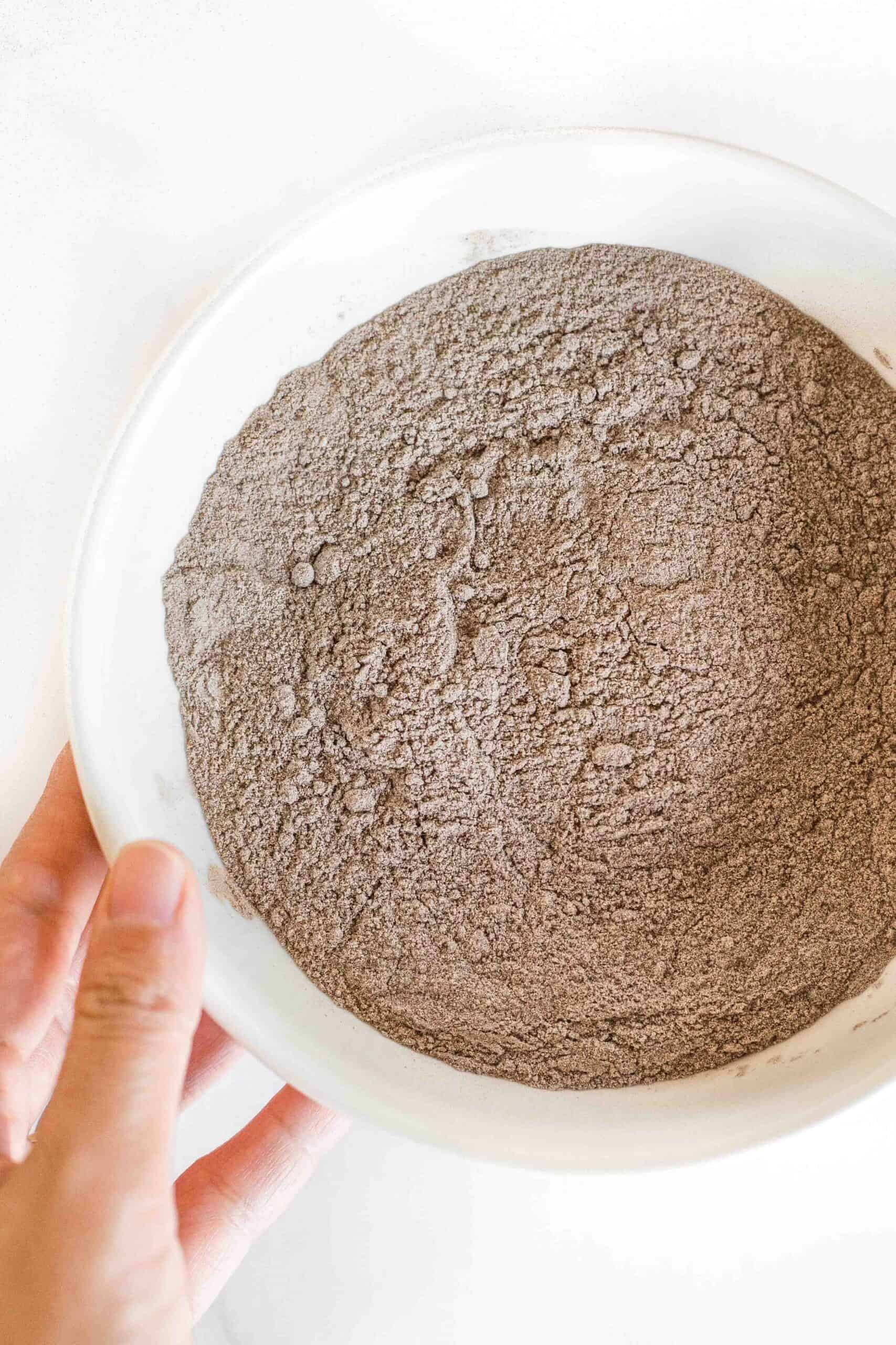 Holding a bowl of teff flour.