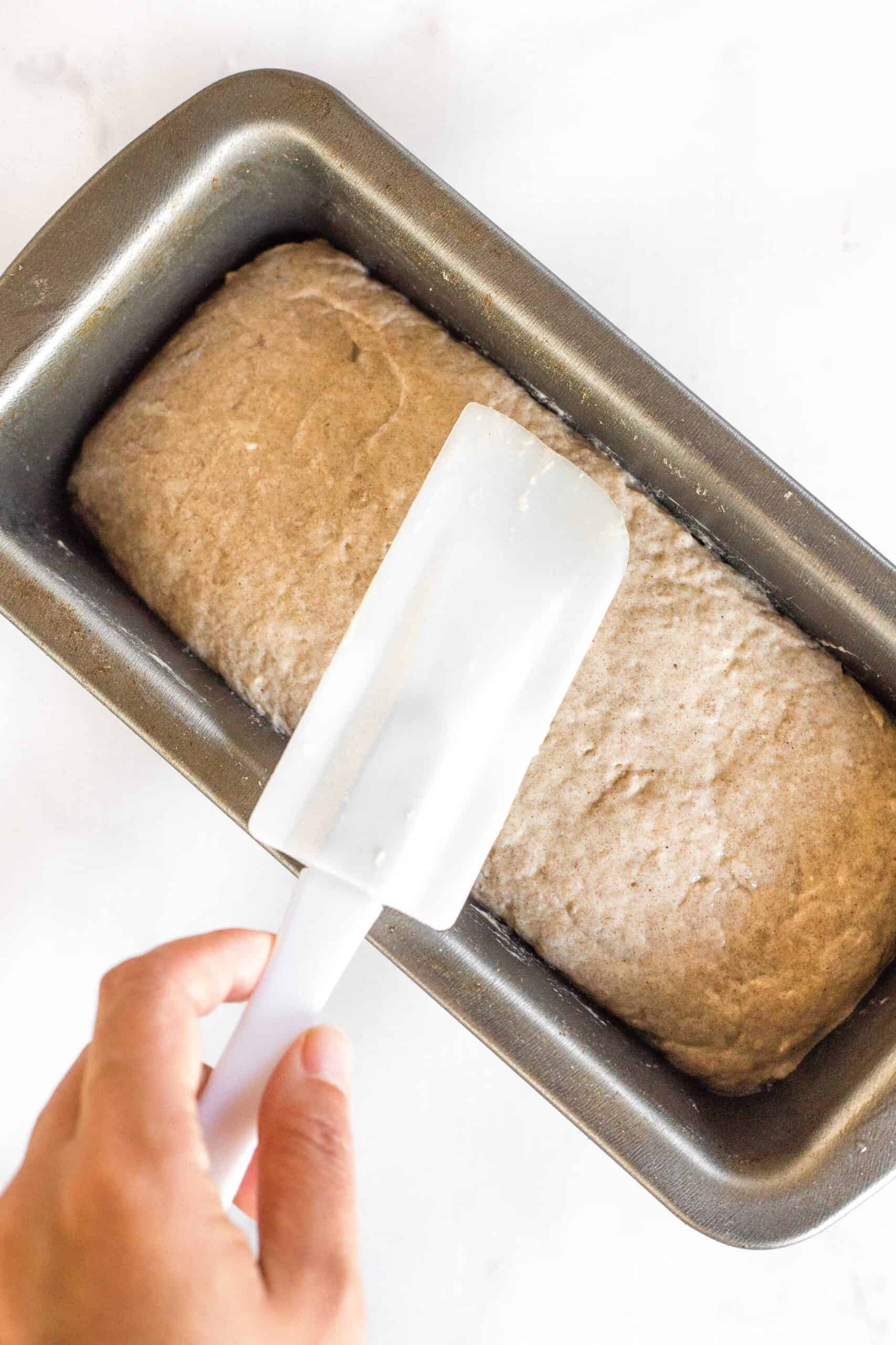 Smoothing out teff bread dough with spatula.