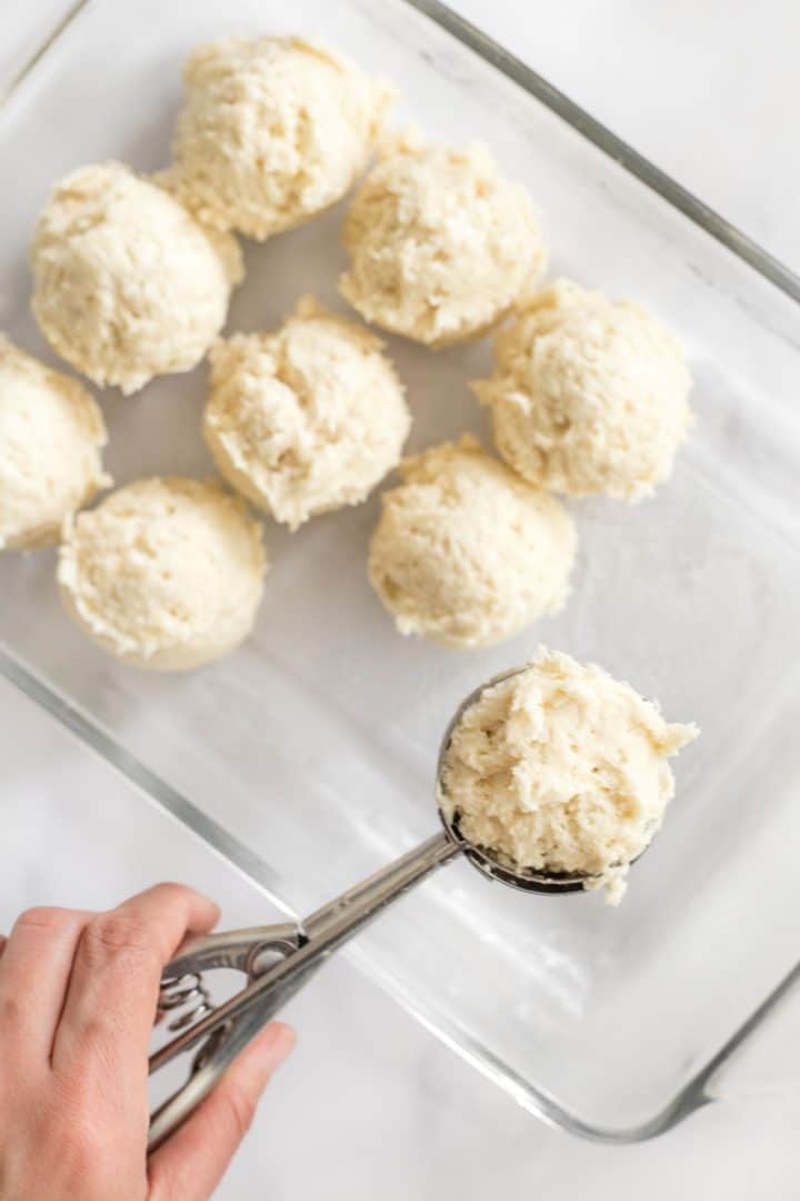 Scooping balls of gluten-free bread dough onto glass pan.