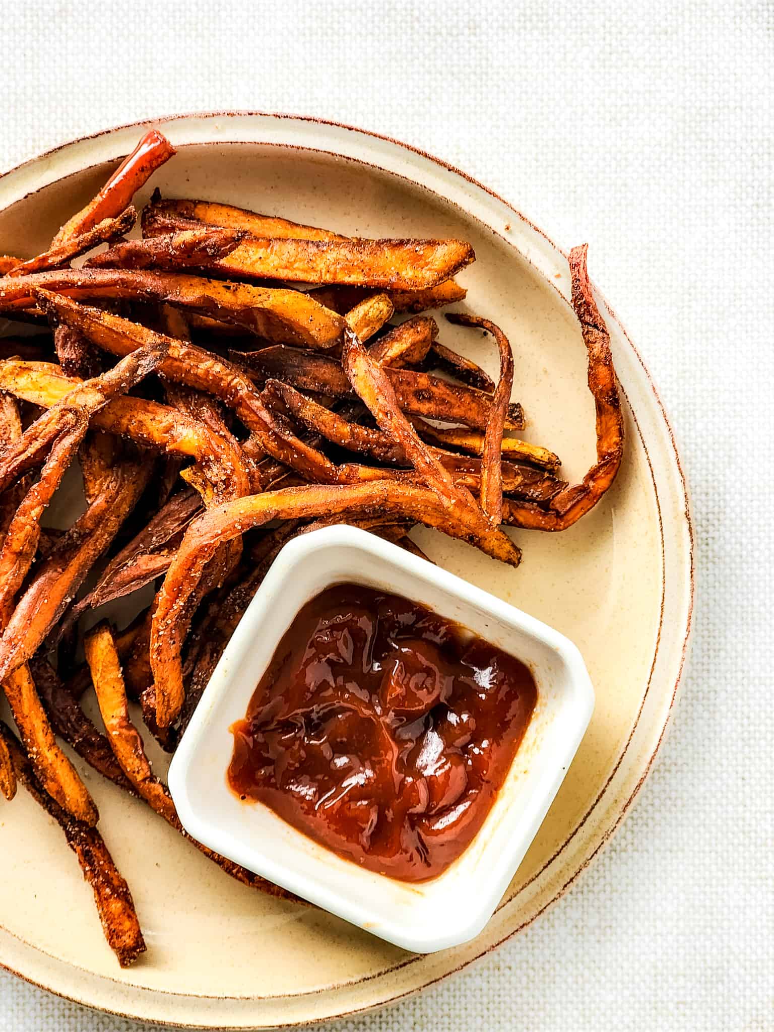 Top down view of a plate of sweet potato fries and ketchup.
