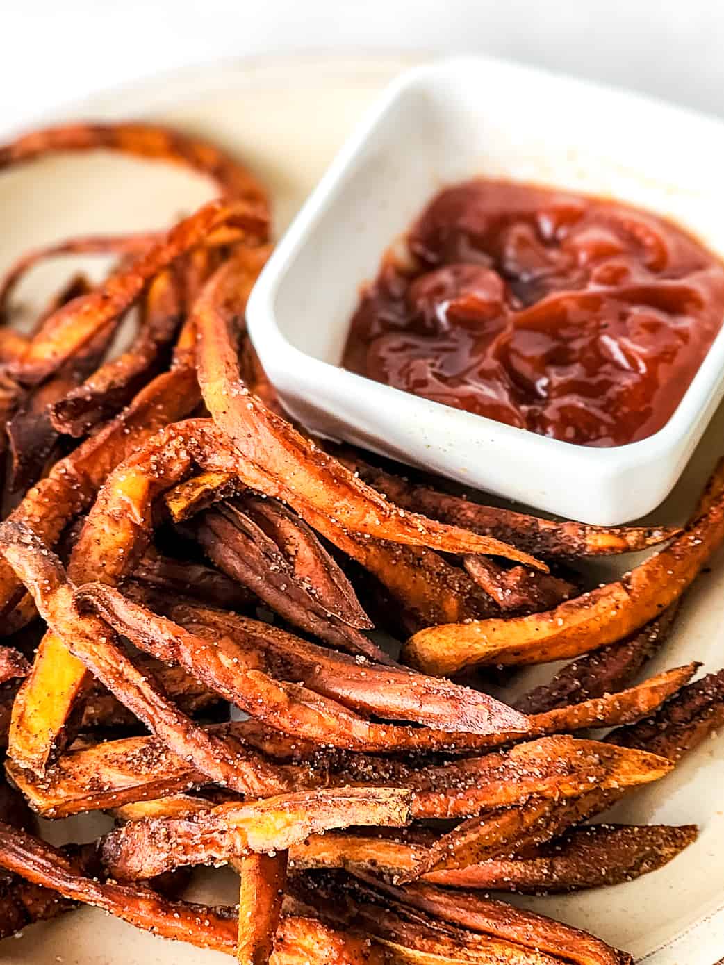 Cinnamon sweet potato fries and ketchup on a plate.