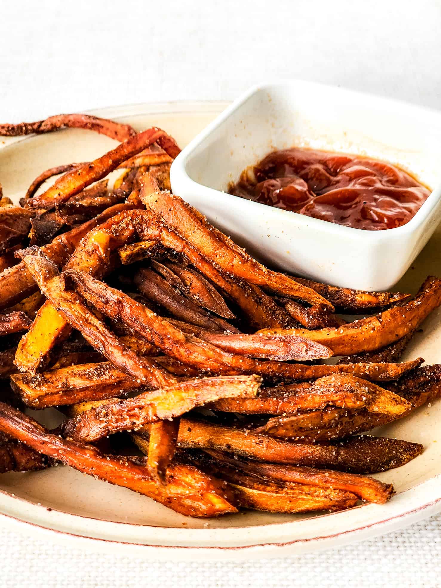 A plate with crispy sweet potato fries and ketchup.