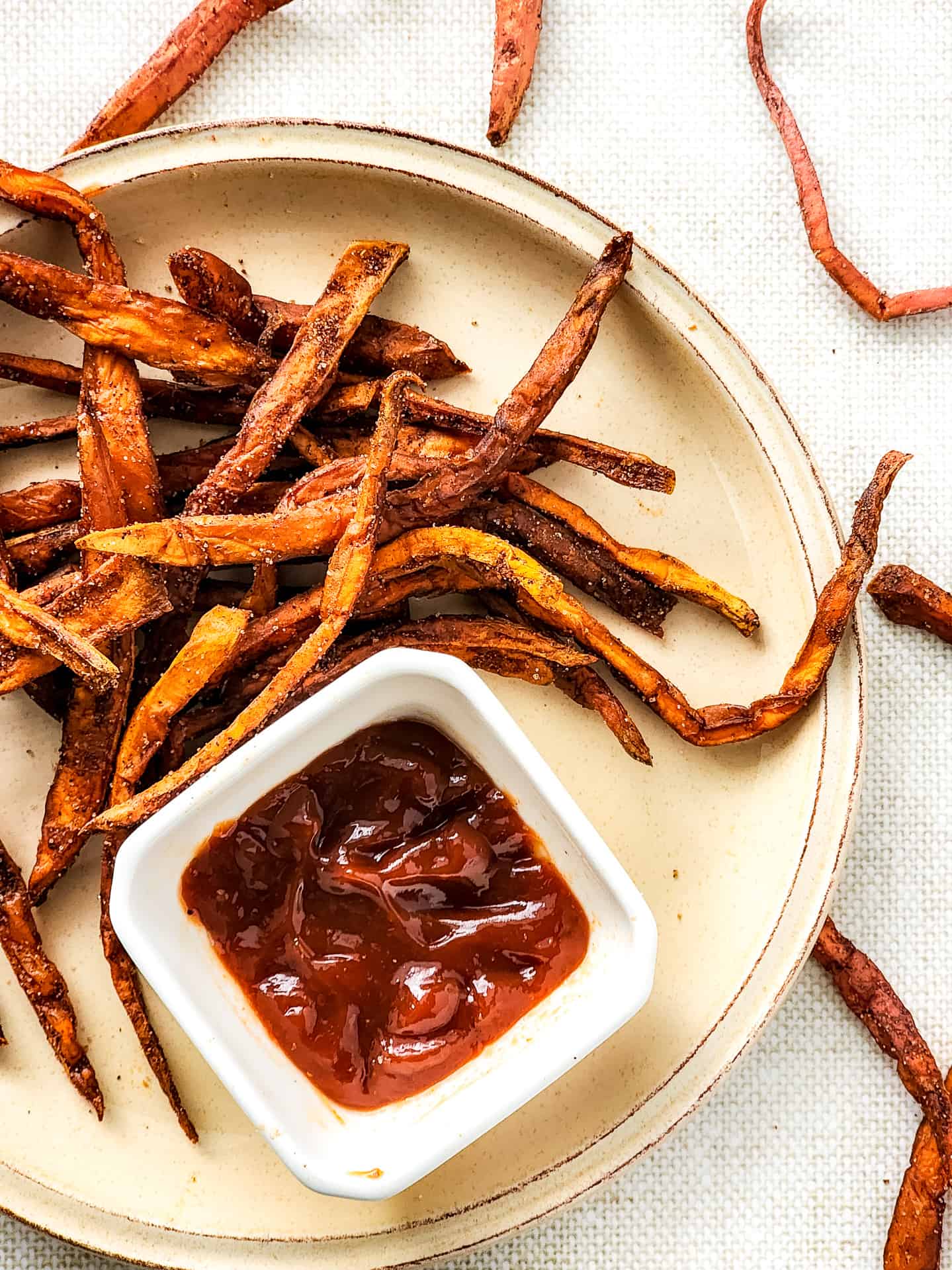 Top down view of sweet potato fries and ketchup on a plate.