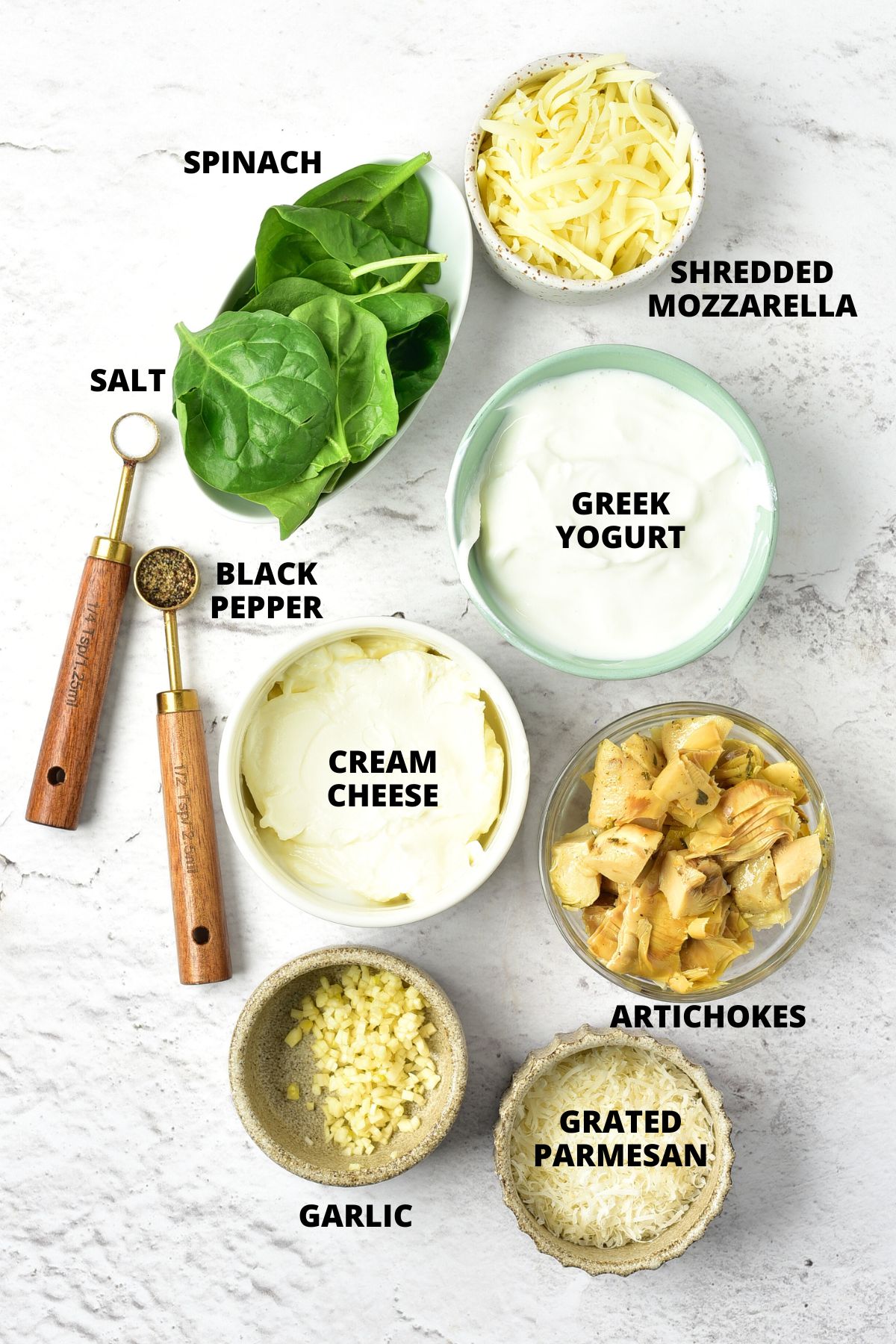 Ingredients for spinach artichoke dip recipe laid out on marble board